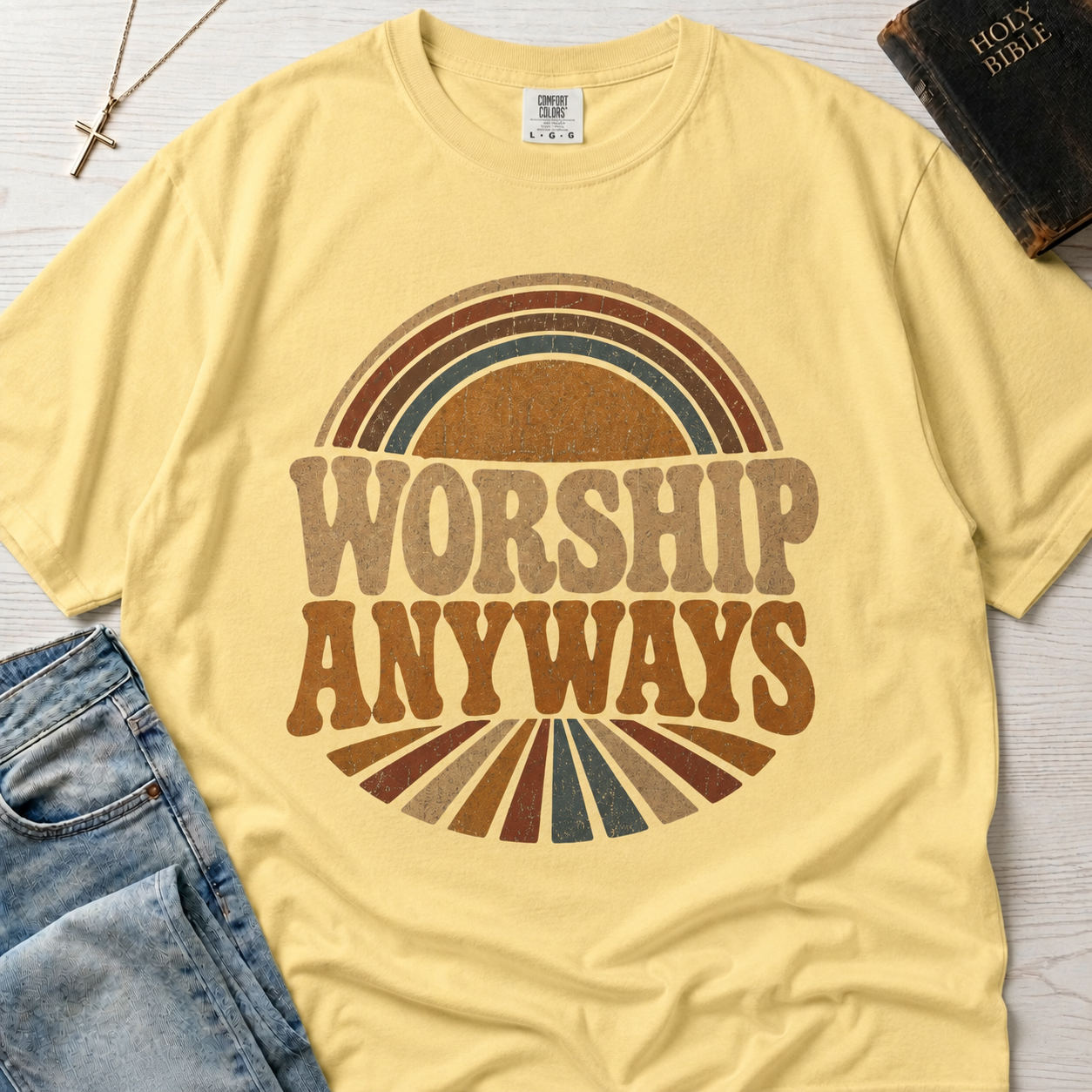 Worship Anyways Christian t-shirt in pale Butter yellow, garment-dyed retro graphic tee with vintage sunburst worship design.
