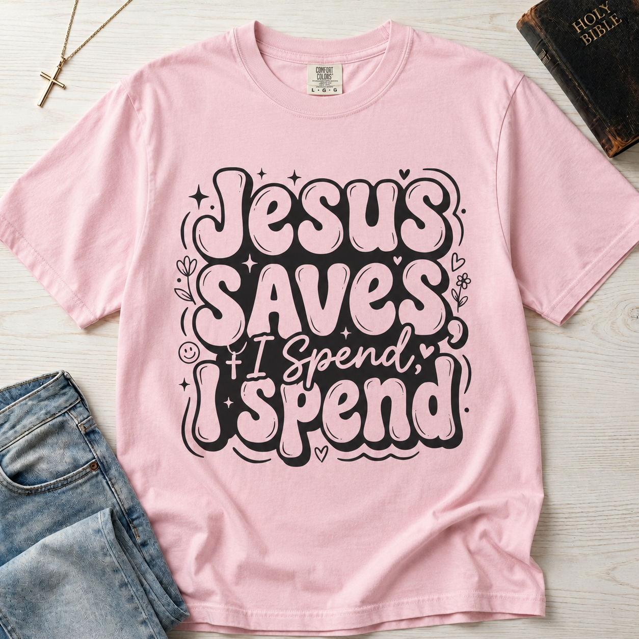 Jesus Saves I Spend Christian humor t-shirt in pastel Blossom pink, playful retro hand-lettered faith graphic tee.