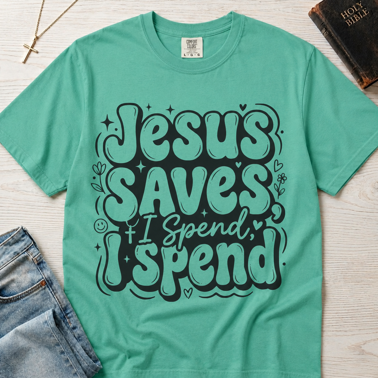 Jesus Saves I Spend Christian humor t-shirt in mint Island Reef green, bold retro stacked typography on garment-dyed cotton tee.