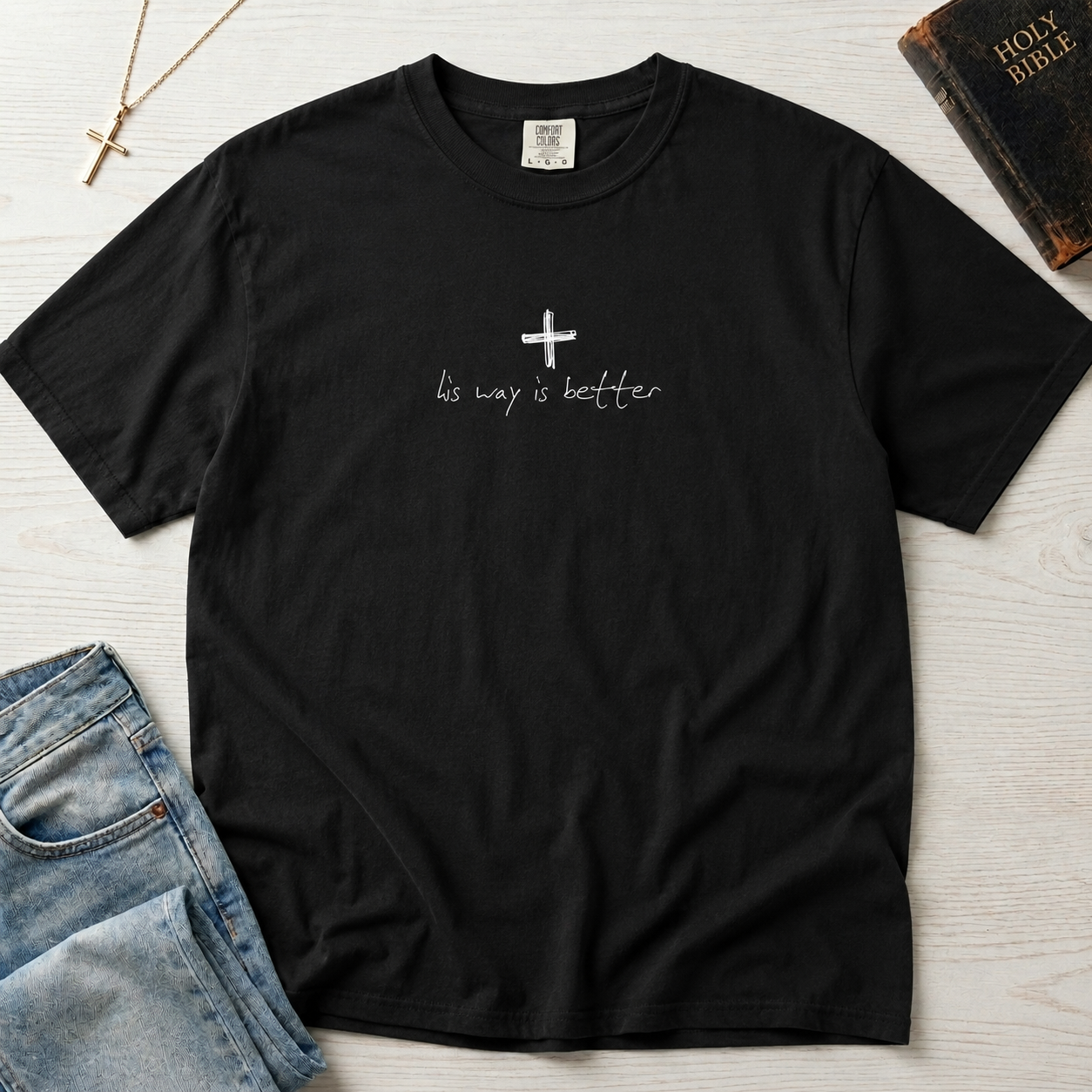Cross & Chill minimal Christian t-shirt in deep graphite, garment-dyed tee with small centered white cross and tiny 'his way is better' script.