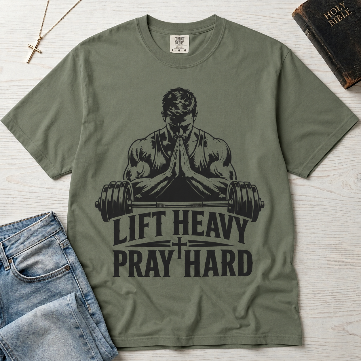 Lift Heavy Pray Hard Christian gym t-shirt in Bay sage green, faith and fitness graphic with praying lifter and barbell illustration, garment-dyed tee.