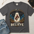 I Still Believe Christian t-shirt in gray; retro graphic of a UFO beaming up a figure over desert cactus at night with 'I Still Believe' banner.
