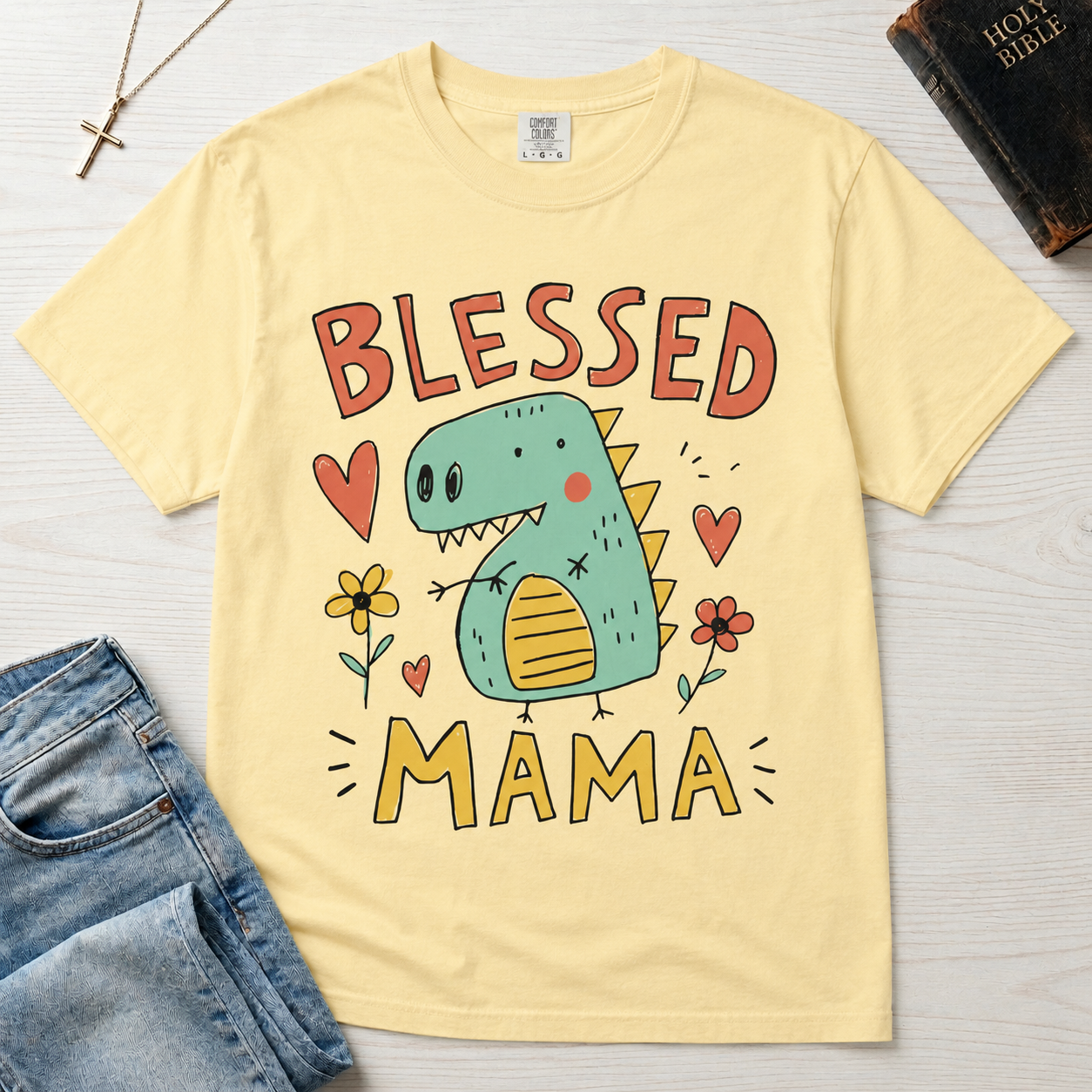 Blessed Mama Dinosaur t-shirt in butter yellow; cute cartoon green dino among flowers and hearts with 'Blessed Mama' lettering, faith mom tee.