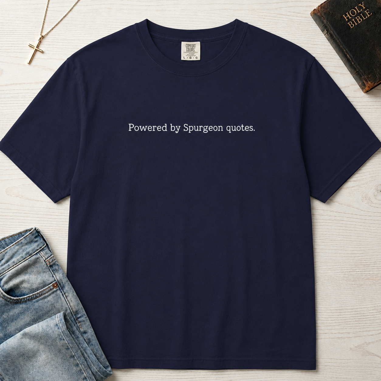 Powered by Spurgeon Quotes Christian t-shirt in slate blue, garment-dyed tee with minimal small centered text 'Powered by Spurgeon quotes'.
