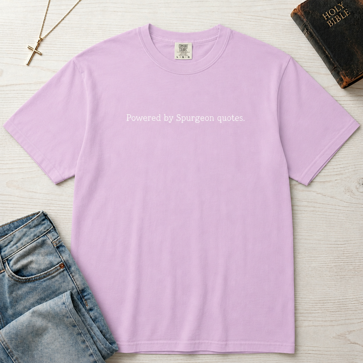 Powered by Spurgeon Quotes Christian t-shirt in lavender, garment-dyed tee with minimal small centered text 'Powered by Spurgeon quotes'.